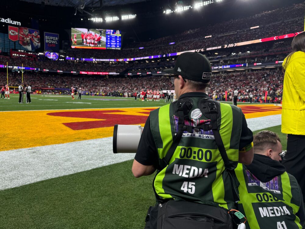 A photographer on a football field, waiting for the game to start.